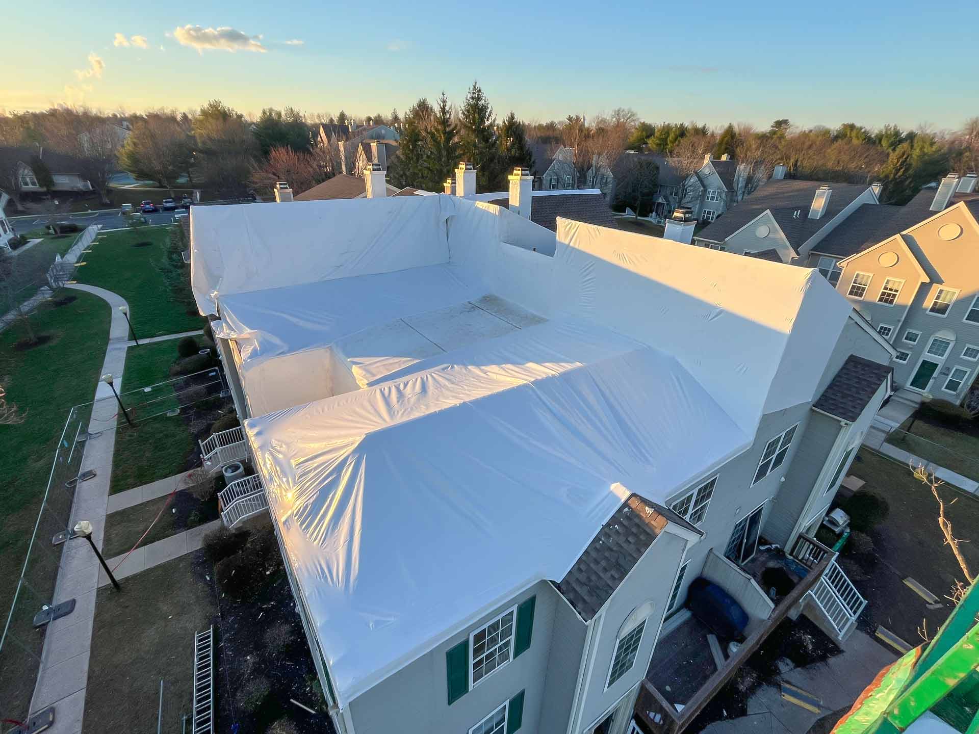 Aerial view of a row of townhouses with a large white tarp covering the roof during renovation