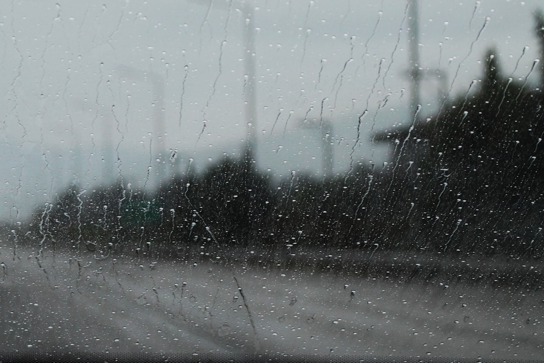 Rain droplets on a glass window, with a blurred cityscape outside on a gray, overcast day