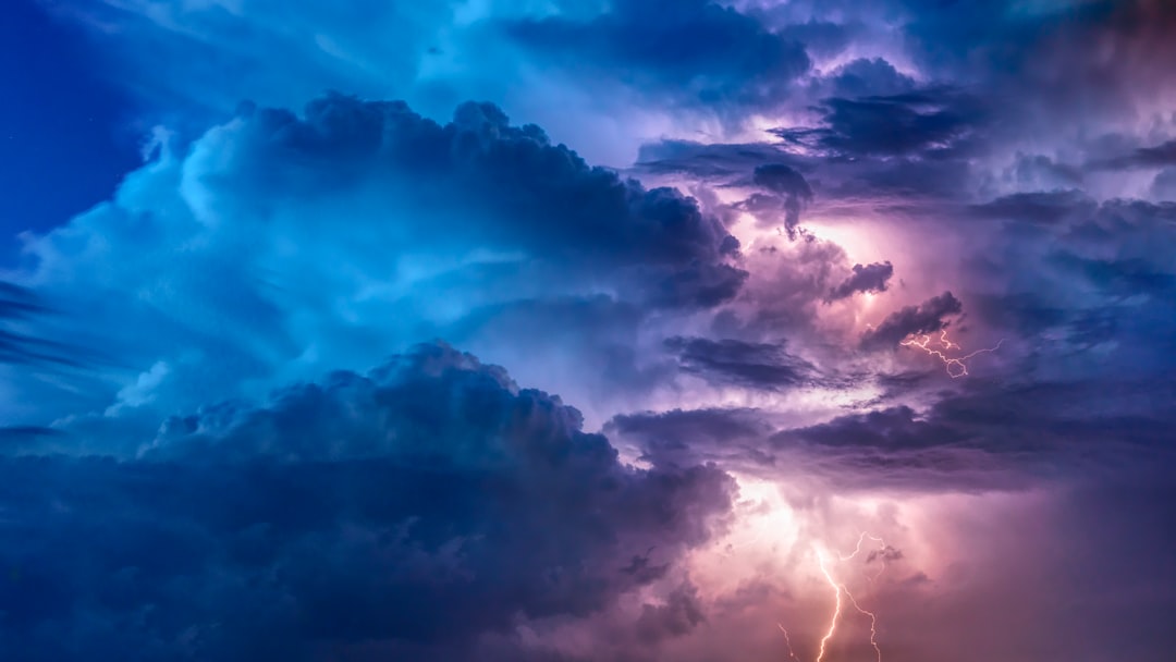 Dark storm clouds with purple lightning streaks across a dramatic night sky.