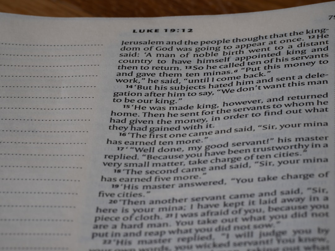 Bible page opened to Luke 19:12 with column of verses visible and dotted margin on left, showing scriptural text.